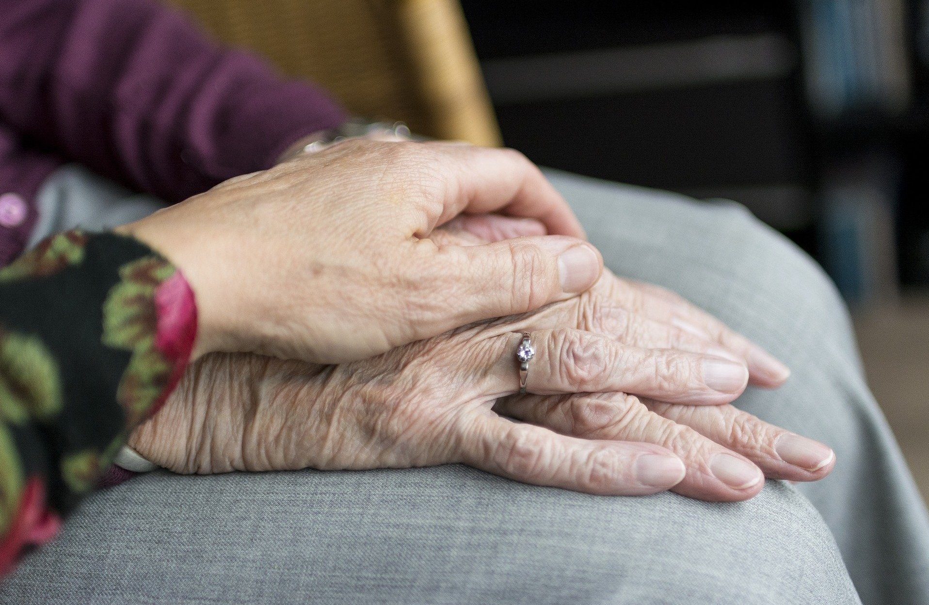 Nahaufnahme von zwei Händen, eine ältere Hand wird fürsorglich von einer jüngeren Hand gehalten